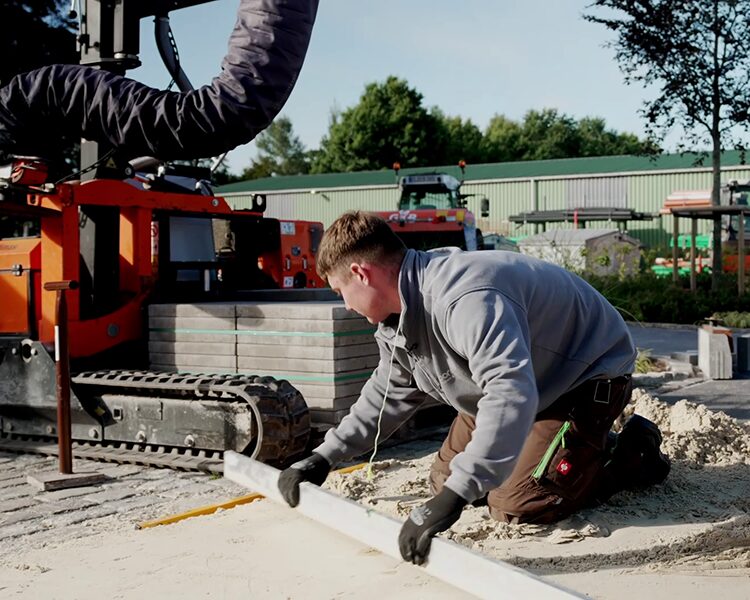 Auszubildender zieht mit Wasserwaage Sandplanum gerade